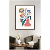 Framed artwork of a pink-striped vase holding abstract flowers in bold colors including blue, orange, yellow, and purple, hung above a modern living room setup.
