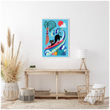 Framed canvas featuring a black cat surfing a red surfboard on stylized blue waves, with a palm tree, red sun, and colorful flowers, hanging above a wooden console table.