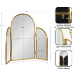 Tri-fold arch mirror with gold metal frame, featuring two side panels that hinge outward and include keyhole hangers for wall mounting or freestanding use.