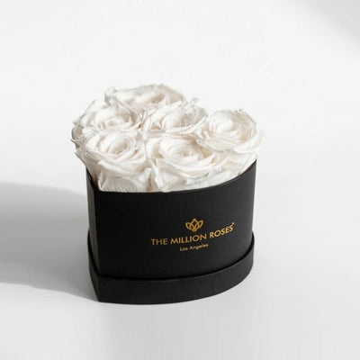 Black box holding six white roses formed into a heart shape