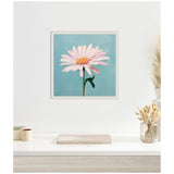 Framed canvas painting of a single pale pink daisy with a yellow center on a teal background, hung above a light wood console with decorative vase and books.