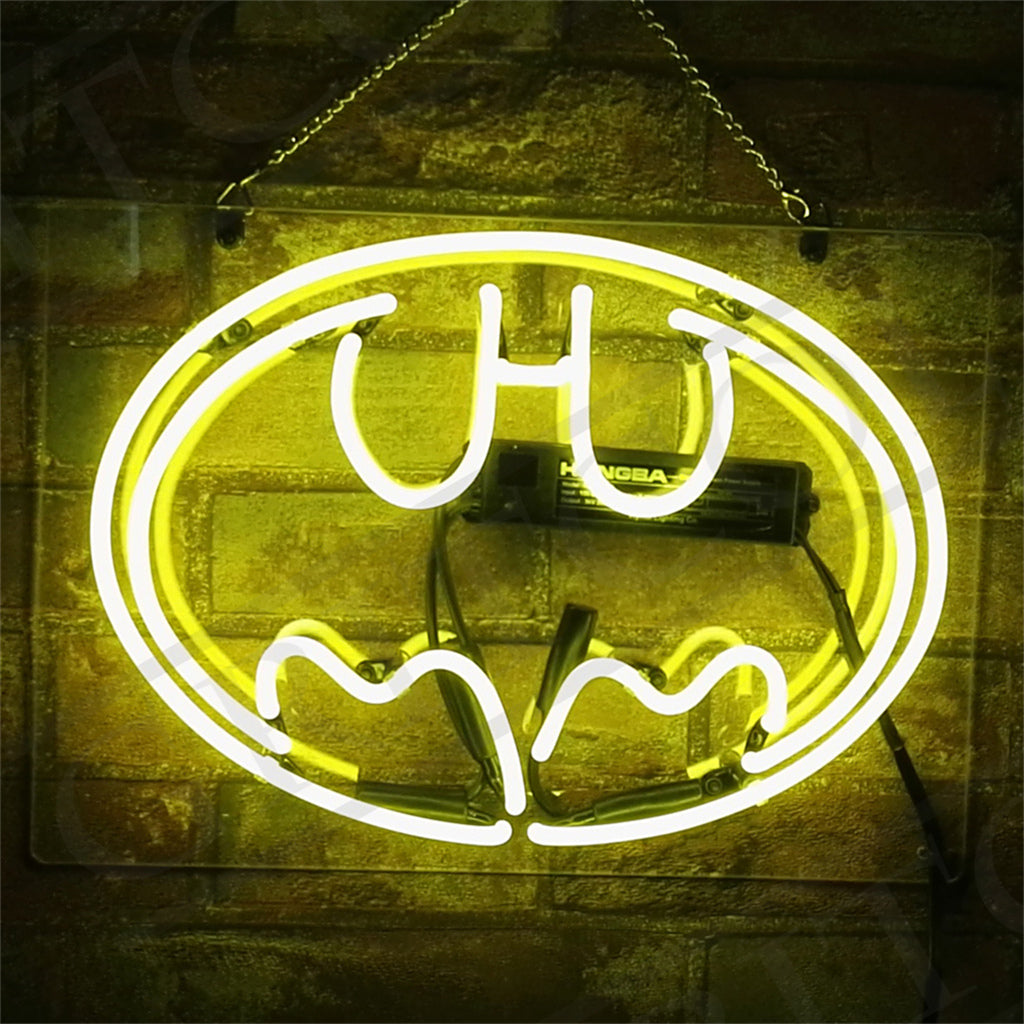 Yellow neon light shaped like the Batman logo mounted on a brick wall with visible wiring and a power pack behind it.