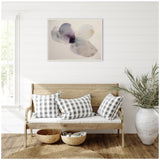 Abstract watercolor flower print with soft purples and grays in a white frame above a light wood bench with black-and-white checkered pillows, surrounded by natural textures.