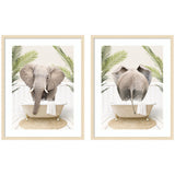Two framed art prints showing a gray elephant in a white clawfoot bathtub from front and back views, surrounded by green palm leaves on a white wooden floor.