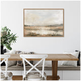 Framed abstract landscape canvas in beige and gray tones hangs above a wooden dining table with white cross-back chairs and cushioned bench seating with patterned pillows.