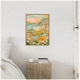 Framed landscape painting above a rustic wooden nightstand with books and a white cup, featuring colorful coastal cliffs and wildflowers under a pastel sky.