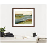 Abstract landscape watercolor print in green, blue, and beige tones framed in dark wood, hanging above a tidy white desk with books, a plant, and a cup.