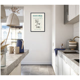 Minimalist kitchen with white cabinets and gray countertops featuring a framed Guest Check artwork with text 'taste one day at a time' on a white wall.
