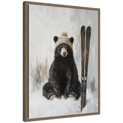 Framed canvas art showing a bear in a knit hat sitting in snow with skis