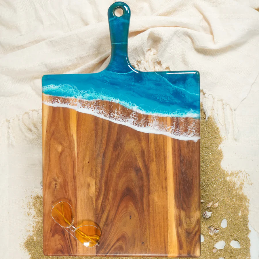 Wooden charcuterie serving tray with blue resin design on a textured surface