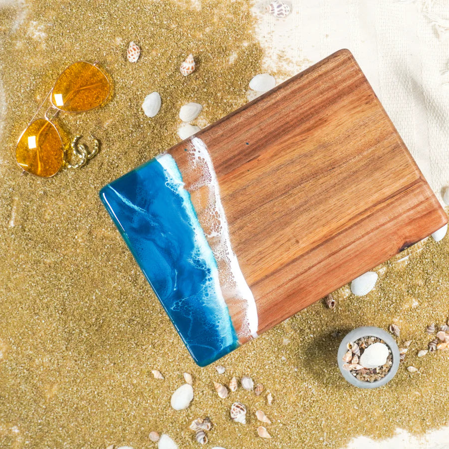 Wooden resin charcuterie board with blue resin on a sandy background