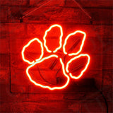 Bright red neon sign shaped like a bear paw with four toes, mounted on a textured brick wall background.