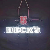 Illuminated neon sign displaying 'BECK'S' in white letters with a red key emblem above, mounted on a black metal frame and hanging by chains against a dark background.