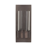Rectangular dark bronze metal wall sconce with vertical ridges and a cylindrical clear glass shade in front.