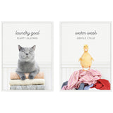 Framed art set featuring a gray cat with closed eyes on folded towels labeled 'laundry goal fluffy clothes' and a yellow duckling standing on colorful clothes labeled 'warm wash gentle cycle'.