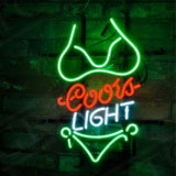 Green neon outline of a bikini top and bottom framing red 'Coors' and white 'LIGHT' text on a dark brick wall background.