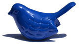 Smooth, glossy blue bird figurine with stylized feather etchings and an upward-pointing tail casting a shadow on a white surface.