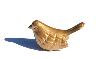 Marigold aluminum bird figurine by Vibhsa sitting on a white surface against a gray background