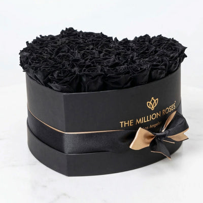 Black heart-shaped box filled with tightly arranged black roses from The Million Roses