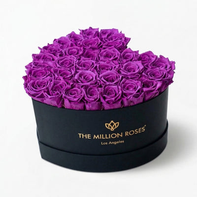 Heart-shaped black box filled with bright purple roses