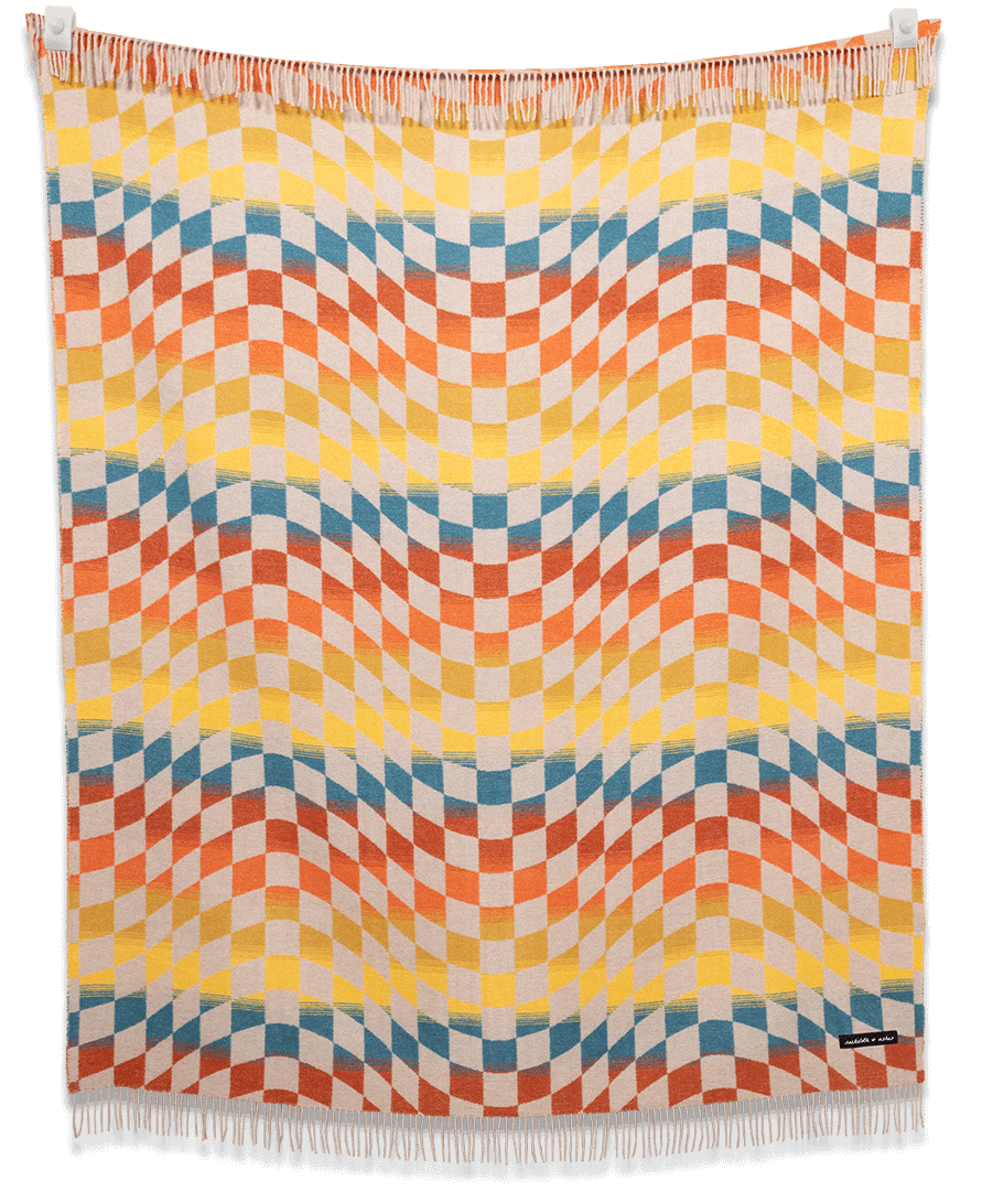 Checkered Santa Cruz blanket draped over a chair showing its geometric pattern and warm colors