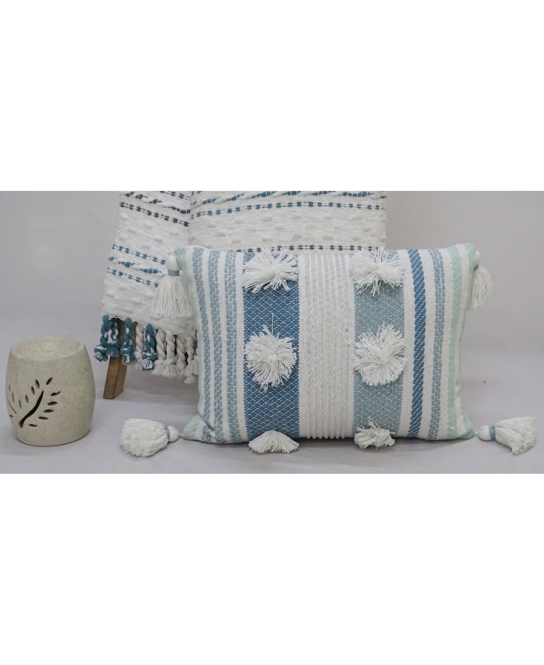 Blue and beige striped throw pillow with large poms and corner tassels on a sofa