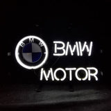 White neon sign featuring a circular BMW logo with blue and white quadrants next to illuminated text 'BMW MOTOR' against a black background.