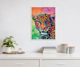 Framed canvas painting of a leopard with vibrant rainbow colors including pink, orange, green, and blue, displayed on a white wall above a white shelf with plants and books.