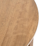 Close-up of a round wooden side table top with a smooth light brown finish and subtle wood grain patterns visible on its surface.