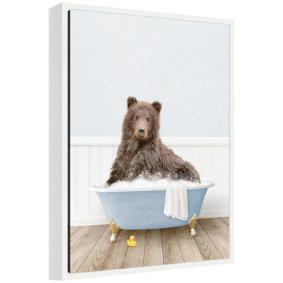 Framed canvas wall art showing a bear soaking in a light blue bathtub, styled with soft neutral wall background