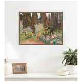 Framed watercolor print of a garden scene with tall dark trees, light foliage, and pink flowers hanging above a white table with a lamp, photo frame, and plant.
