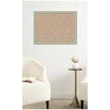 Beige cork pinboard with a white lattice pattern framed in light gray, hung on a white wall between two white upholstered chairs and a brass side table with a white vase