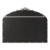 Back of a traditional arch-shaped mirror with a carved ornamental crest on top and multiple metal clips securing black backing material.