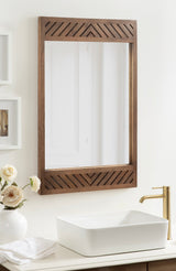 Rectangular wall mirror with walnut wood frame featuring angled geometric inlays on top and bottom, mounted above a white vessel sink and gold faucet.
