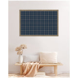 Rectangular navy blue plaid fabric pinboard with white grid lines, framed in light wood, mounted on a white wall above a wooden bench with beige and white cushions and a beige throw.