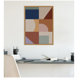 Geometric abstract wall art with navy, beige, rust, and muted purple shapes in a wooden frame above a minimalist desk setup.