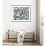 Framed abstract artwork with colorful rectangular shapes in blue, orange, gray, and white, hanging on a white wall above a wooden bench with a draped cloth and open book.