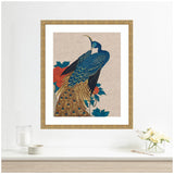 Decorative framed print of a blue and gold peacock perched beside red and dark teal peony flowers on a neutral linen background, displayed above a light wood shelf.