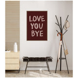Maroon framed wall art with large beige hand-painted text saying 'LOVE YOU BYE' above a black cushioned bench, next to a black coat rack holding a hat, umbrella, and bag.