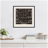 Black and white framed print of Henri Matisse's 1938 'Corbeille de begonias' depicting stylized begonia leaves in a decorative vase on a grid background, hung above a modern white sideboard with plants and books.