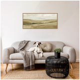 Modern living room with light gray sofa, textured gray throw and round beige pillow, black circular wicker coffee table with small green plant, and neutral-toned landscape painting above sofa.