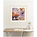 Abstract floral artwork with overlapping leaves in shades of mauve, pink, rust, and olive, framed in light wood and hung above a minimalist wood desk.