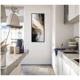 Tall, narrow framed abstract canvas featuring flowing black, white, and gold brushstrokes hanging on a white kitchen wall between concrete countertops and modern cabinetry.