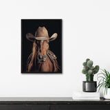Framed print of a brown horse wearing a worn tan cowboy hat and a leather saddle, set against a black background, hanging on a white wall above a black surface with potted cacti.