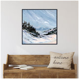 Framed oil painting of a snow-covered mountain valley with evergreen trees under a cloudy blue sky, hung above a wooden bench with a 'welcome home' pillow and open book.