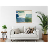 Abstract framed canvas with overlapping blue and green shapes hangs above a white sofa adorned with patterned and solid pillows, flanked by green potted plants.