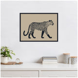 Framed linocut-style print of a black spotted leopard walking on a beige background, hanging above a white cabinet with plants and books.