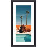 A large brown bison lying on concrete beside a turquoise swimming pool with an orange wall and two tall palm trees under a clear blue sky.