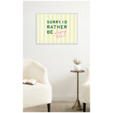 Framed canvas wall art with pale yellow vertical stripes and text reading 'SORRY, I'D RATHER BE playing tennis' in green and pink fonts, hung above a small brass side table and cream armchairs.