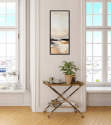 Vertical abstract landscape painting in muted beige, gray, and black tones above a gold and wood bar cart with a potted plant, cup, and bowls in a bright room with large windows.